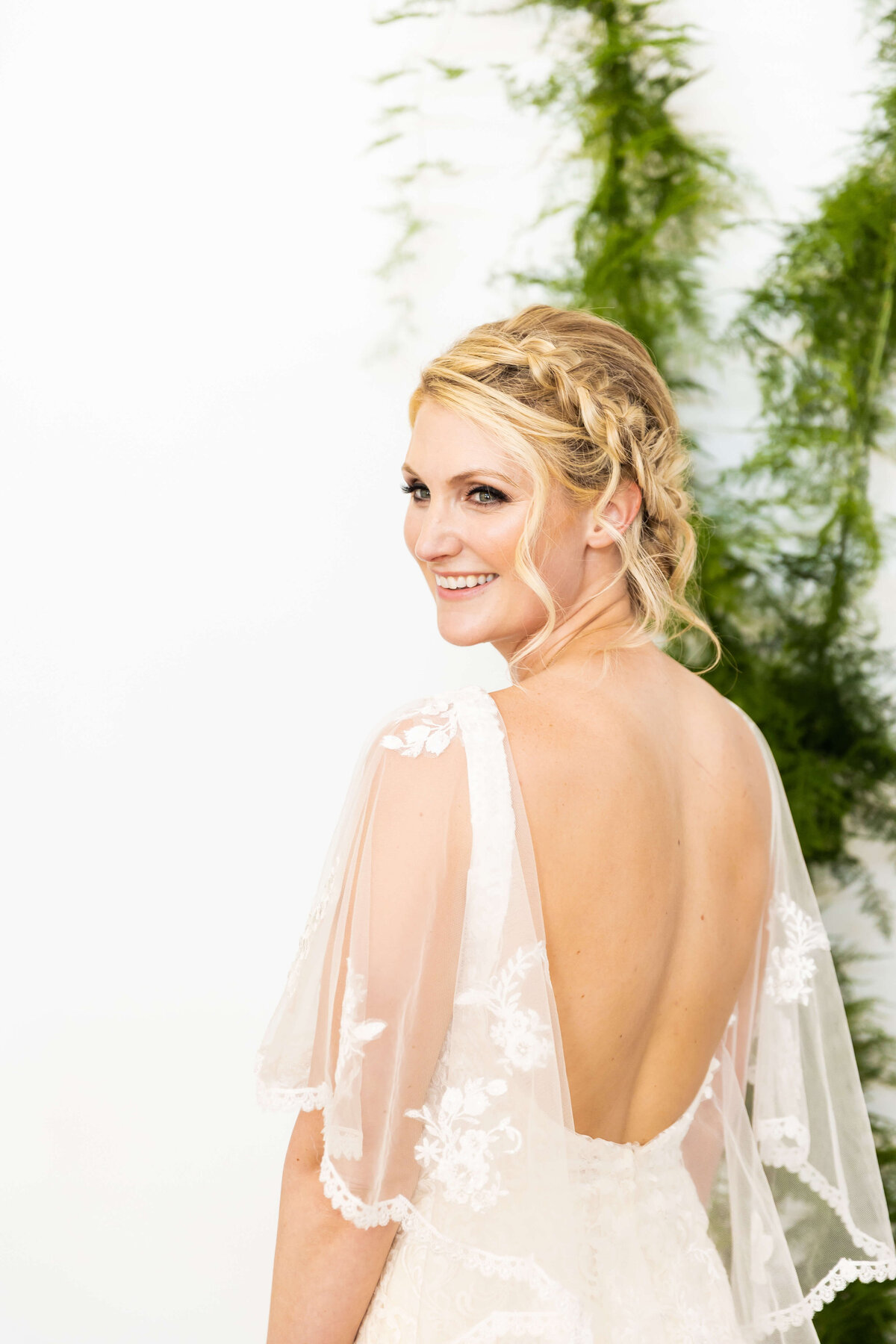 Bride with hair in braids with low backed wedding gown with lace sleeves  designed by Winnie Couture