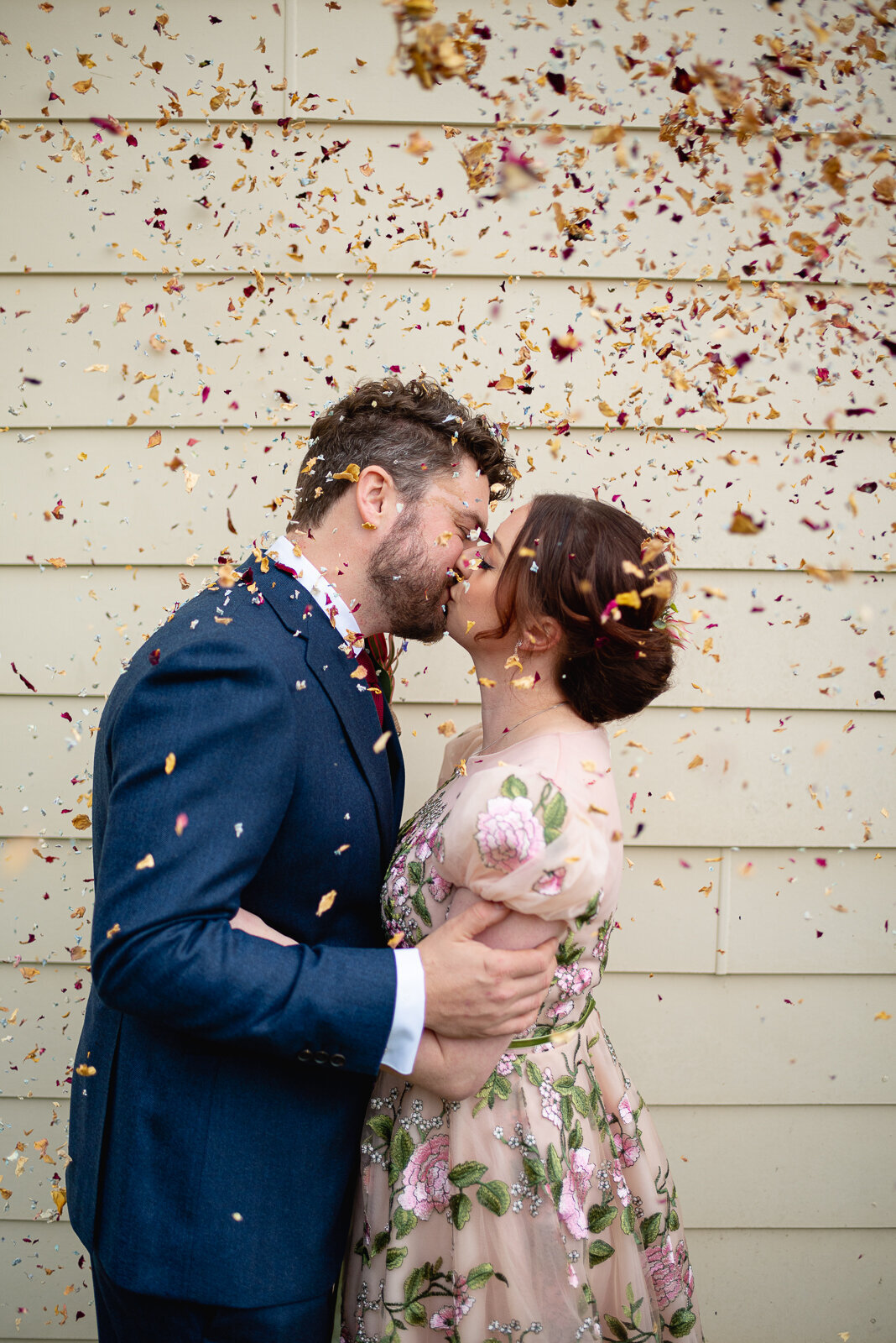 Bride and Groom kissing with confetti in the air