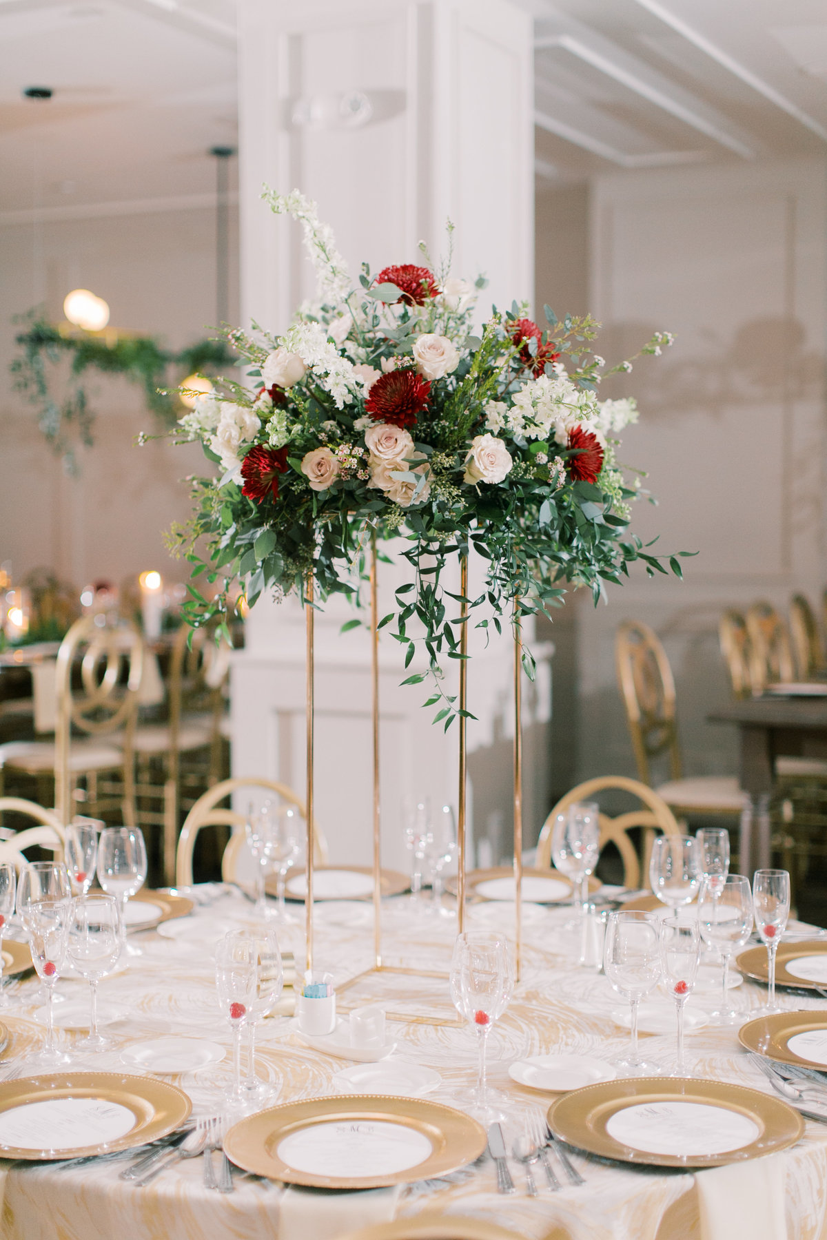 tall gold centerpiece with white, red, and green flowers