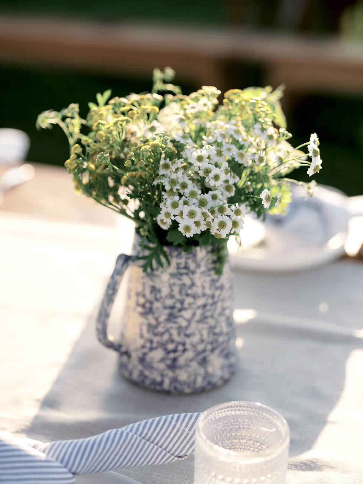 A pretty flower centerpiece is on a dining table outdoors, at Lion Rock Farms, CT. Image by Jenny Fu Studio