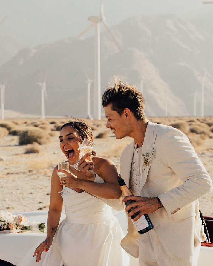 Bride and groom celebrate with champagne at the windmills in palm springs