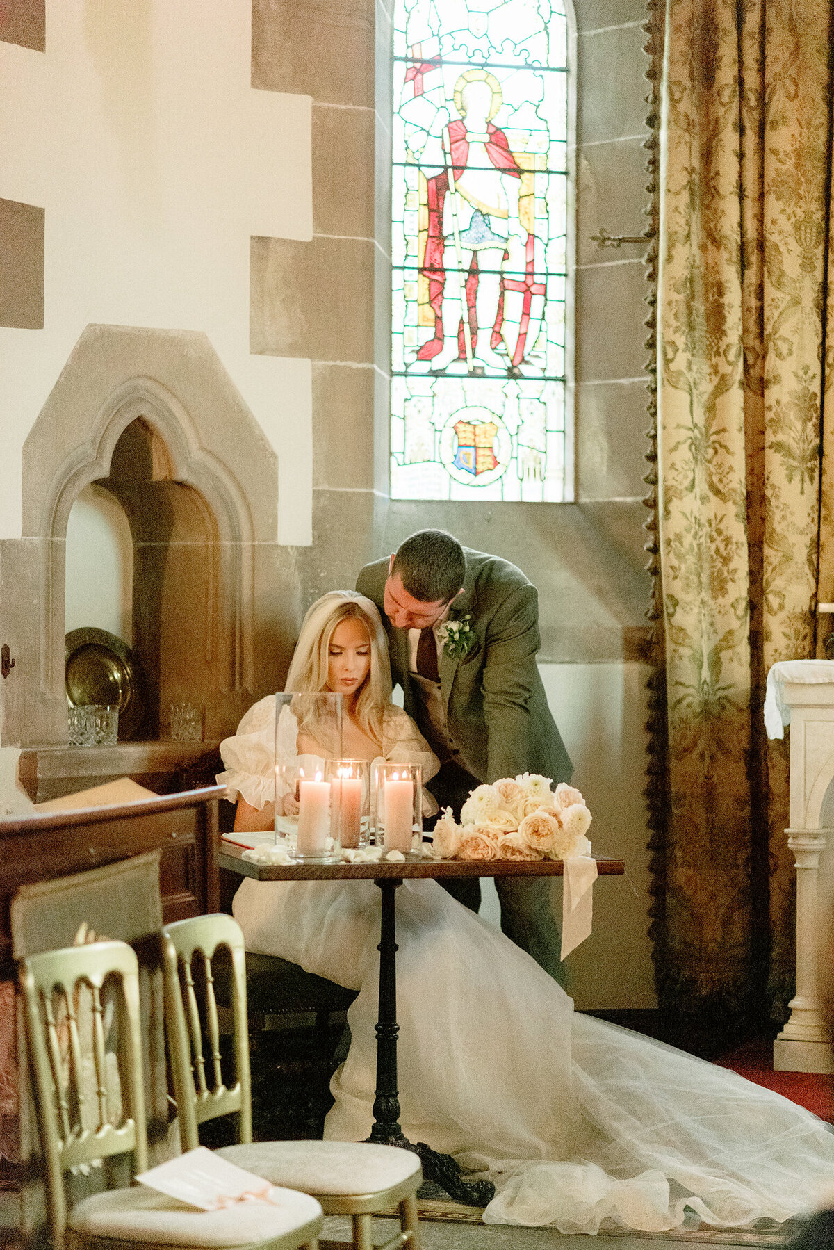 Stunning emotive wedding photograph of Bride and Groom signing register by candlelight in the Cromlix House Chapel, Scotland.