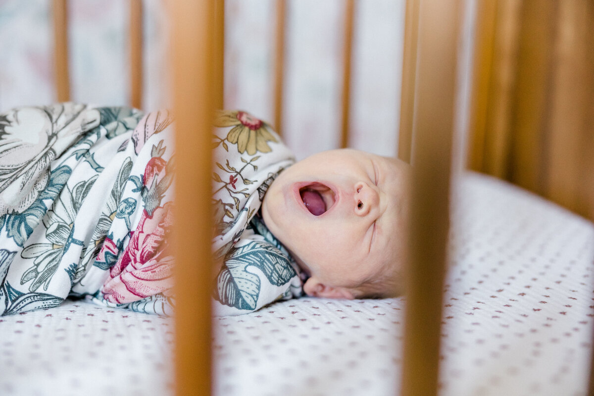 baby laying in crib yawning