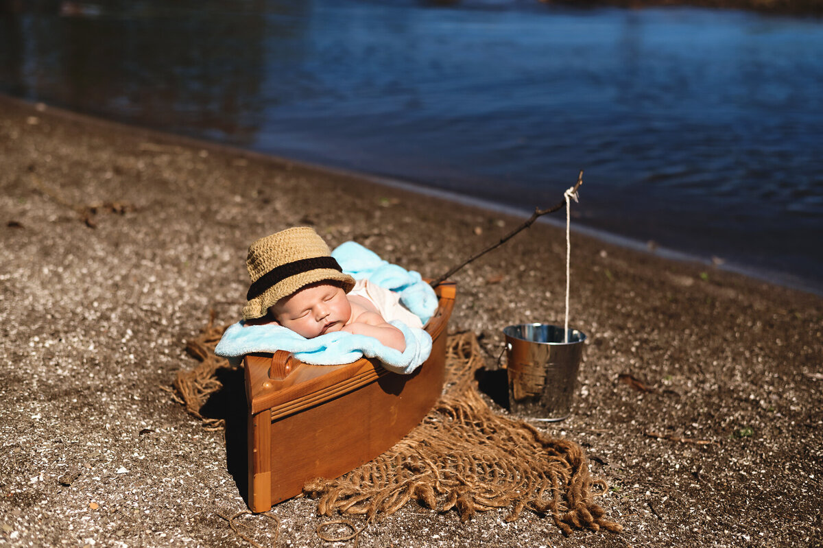 Baby boys asleep in a canoe by a lake at his outdoor newborn photos in the greater Toronto area at The Pumphouse.