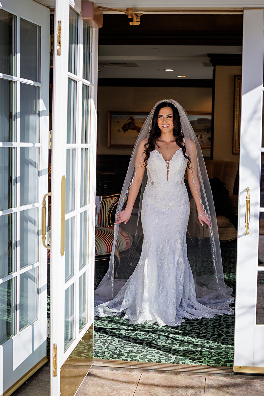 Bride smiles in the window on her wedding day at The Broadmoor Hotel in Colorado Springs, Colorado.