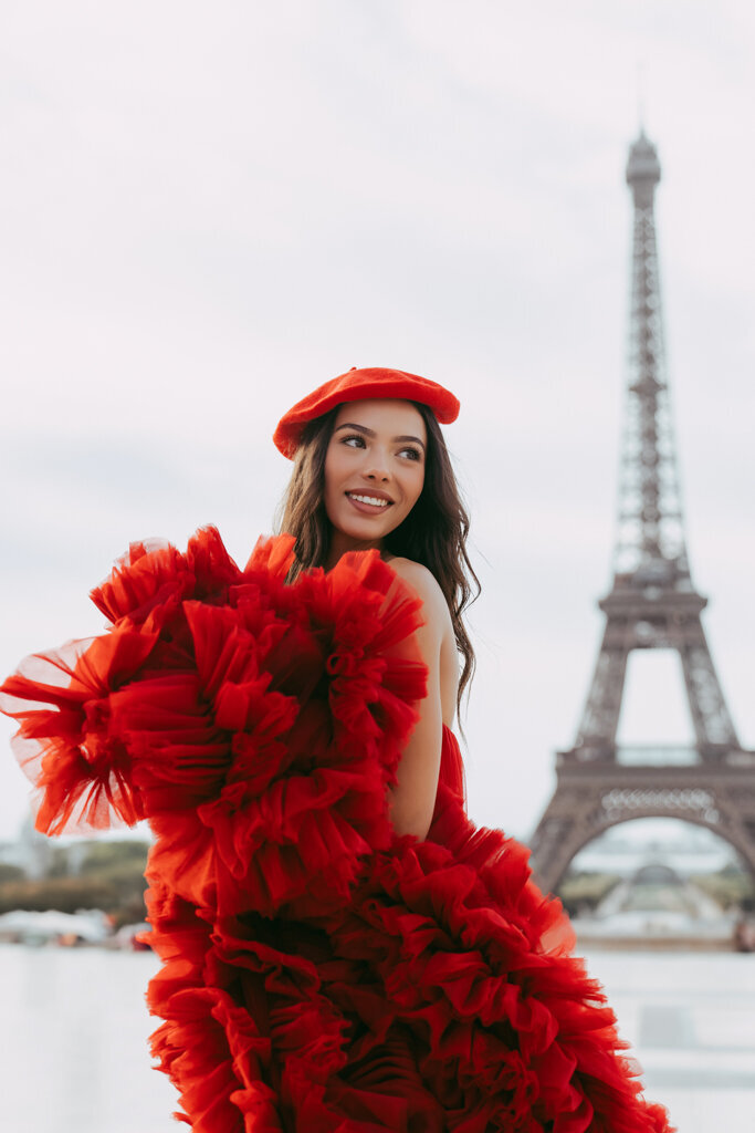 Paris portrait session with brunette holding voluminous red dress and matching beret before Eiffel Tower