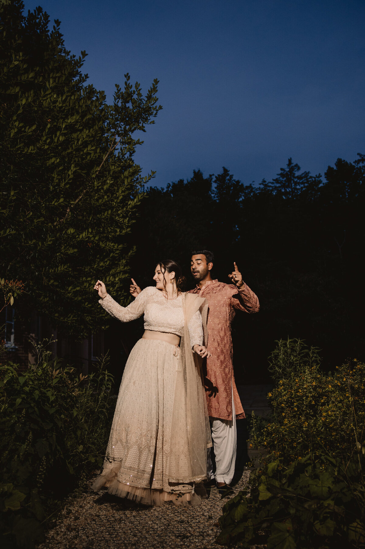 A newlywed couple dancing on a small path between bushes 