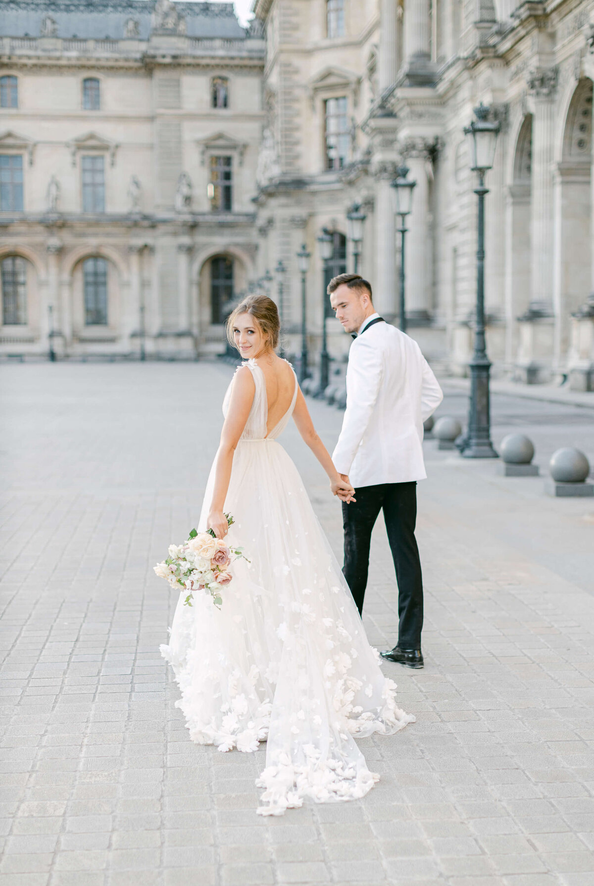 A bride and groom walk in the courtyard of the Louvre