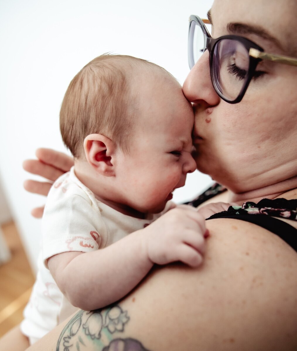 A new mama kisses her 2 day old baby