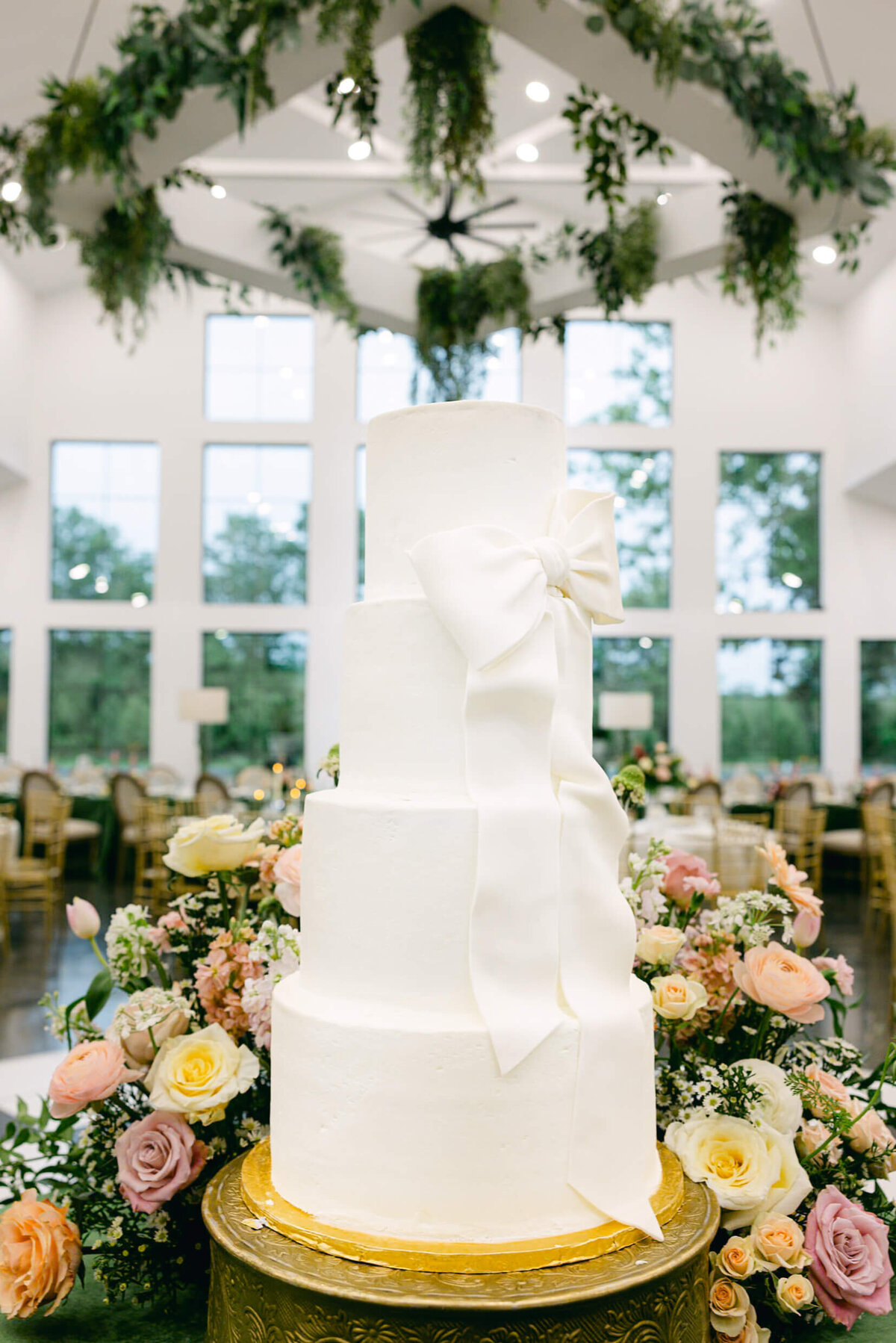 A wedding photo of the white wedding cake surronuded by flowers