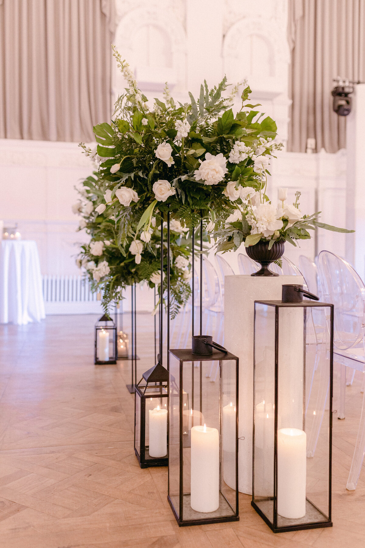 An arrangement of exotic greenery and white flowers decorates the aisle of a wedding at Maison Principale. 