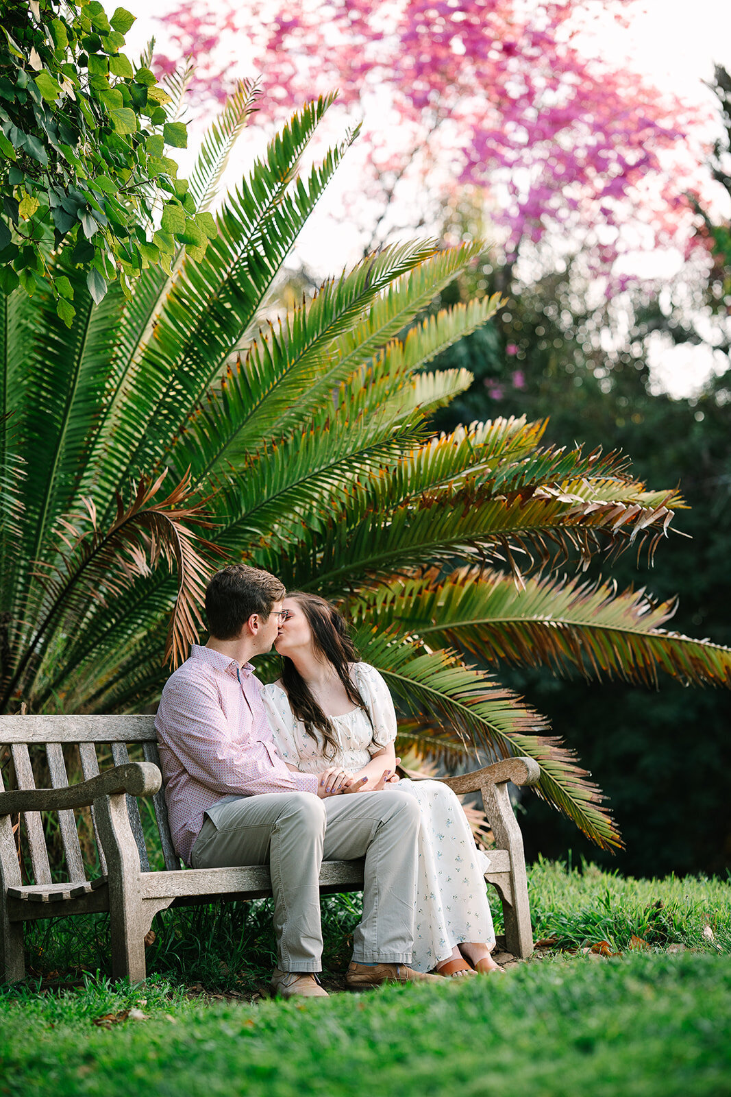 A couple sitting on a bench together kissing. 