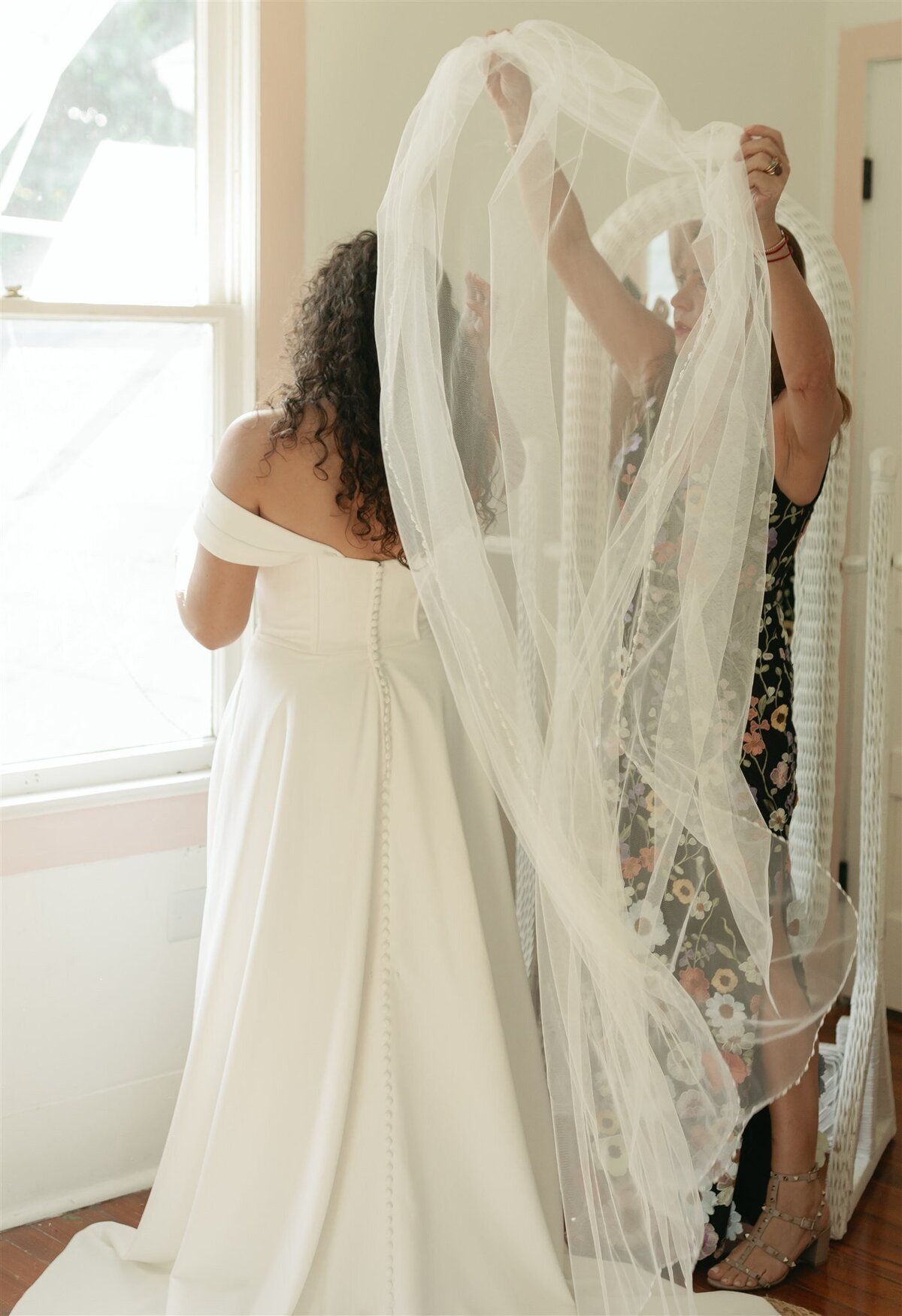 Bride's mother helping to put on wedding veil during the getting ready portion of the wedding day