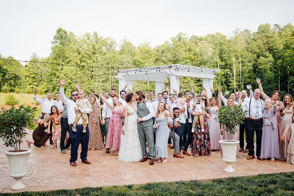 wedding guests celebrating as bride and groom kiss