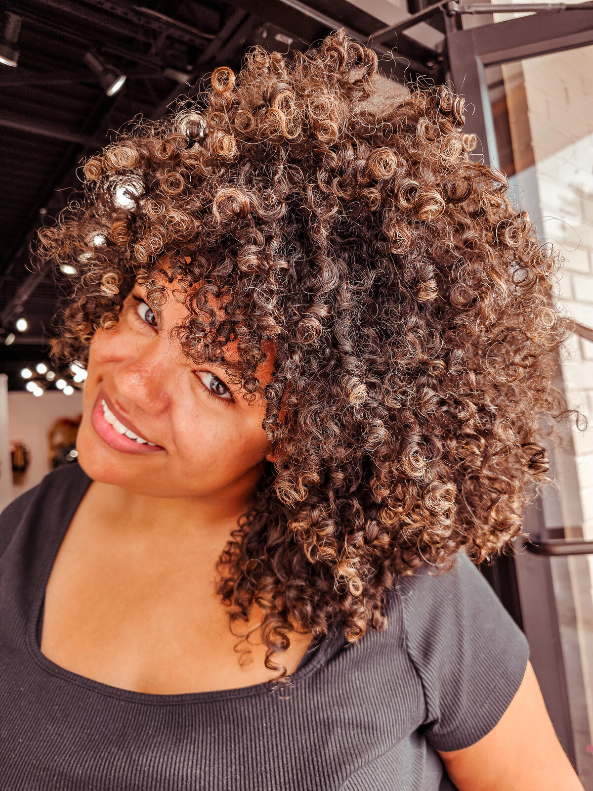 Tight, coily curly hair in a big round shape courtesy of Moxie by KC