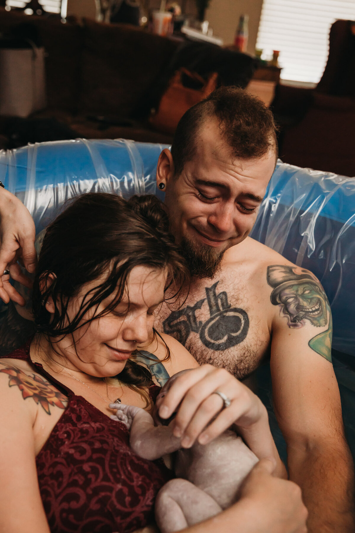 woman and man in birth pool holding newborn