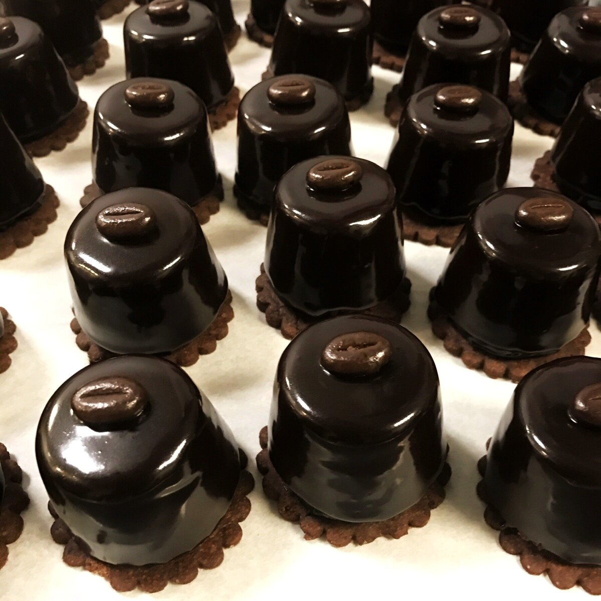Mini coffee and chocolate petits fours with shiny chocolate glaze and espresso  bean