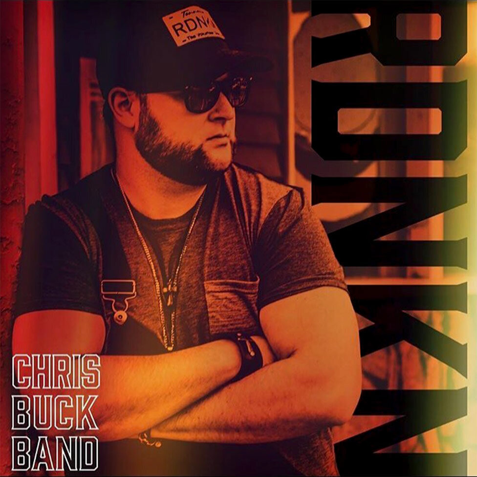 Nashville Single Cover Title RDNKN Artist Chris Buck Band singer standing with arms folded across his chest wearing baseball cap and sunglasses black and white image toned red yellow and orange