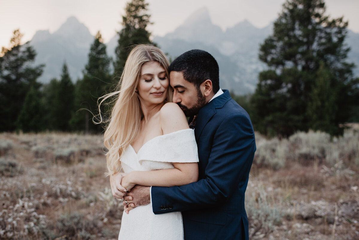 Photographers Jackson Hole capture bride and groom kissing while hugging