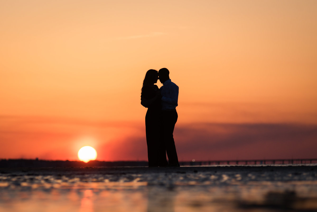 silhouette of couple at sunset on virginia beach during engagement session by va engagement photographer