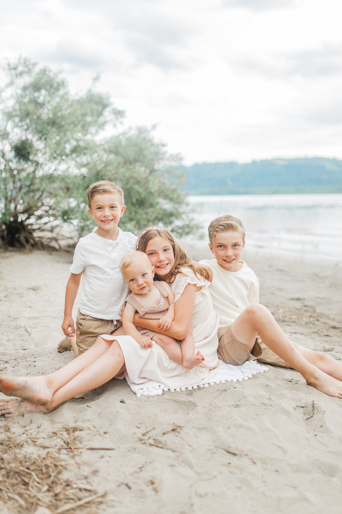 Four children sitting on a beach blanket