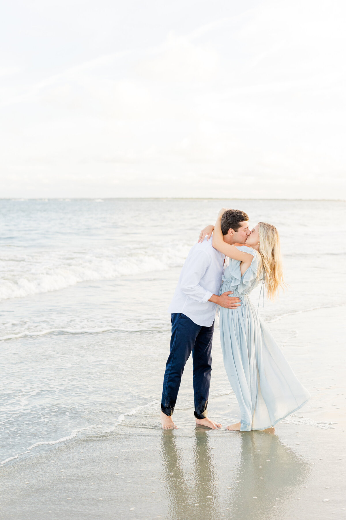 engaged couple kissing near the ocean
