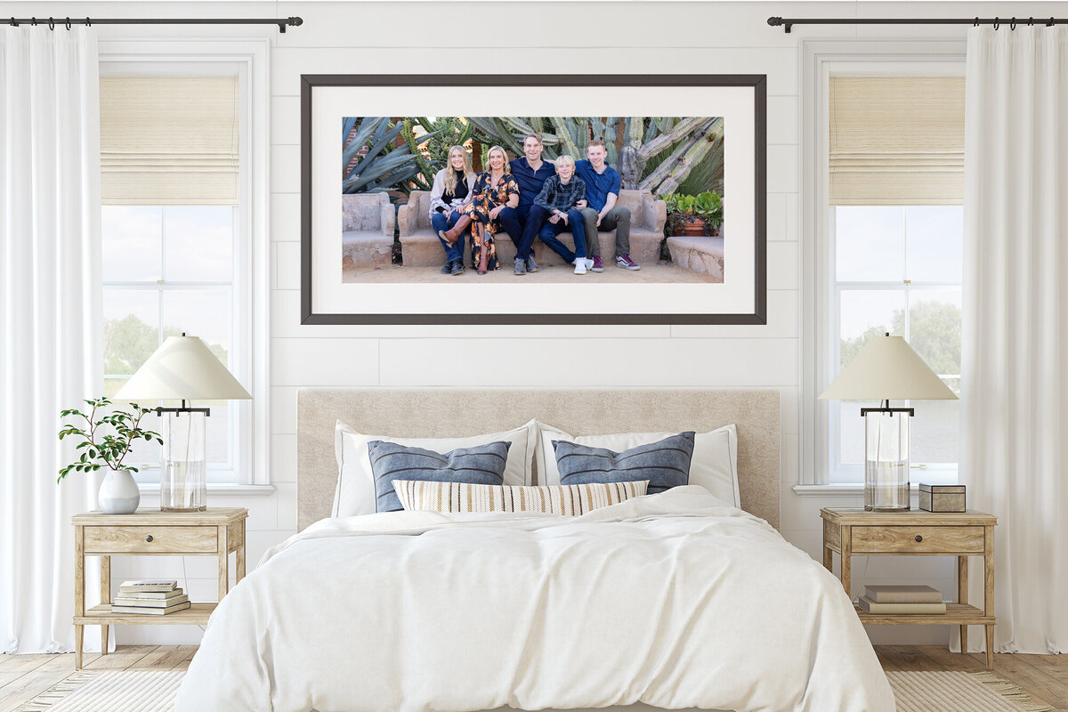 A modern white bedroom with portrait of smiling family of five hanging above the bed.