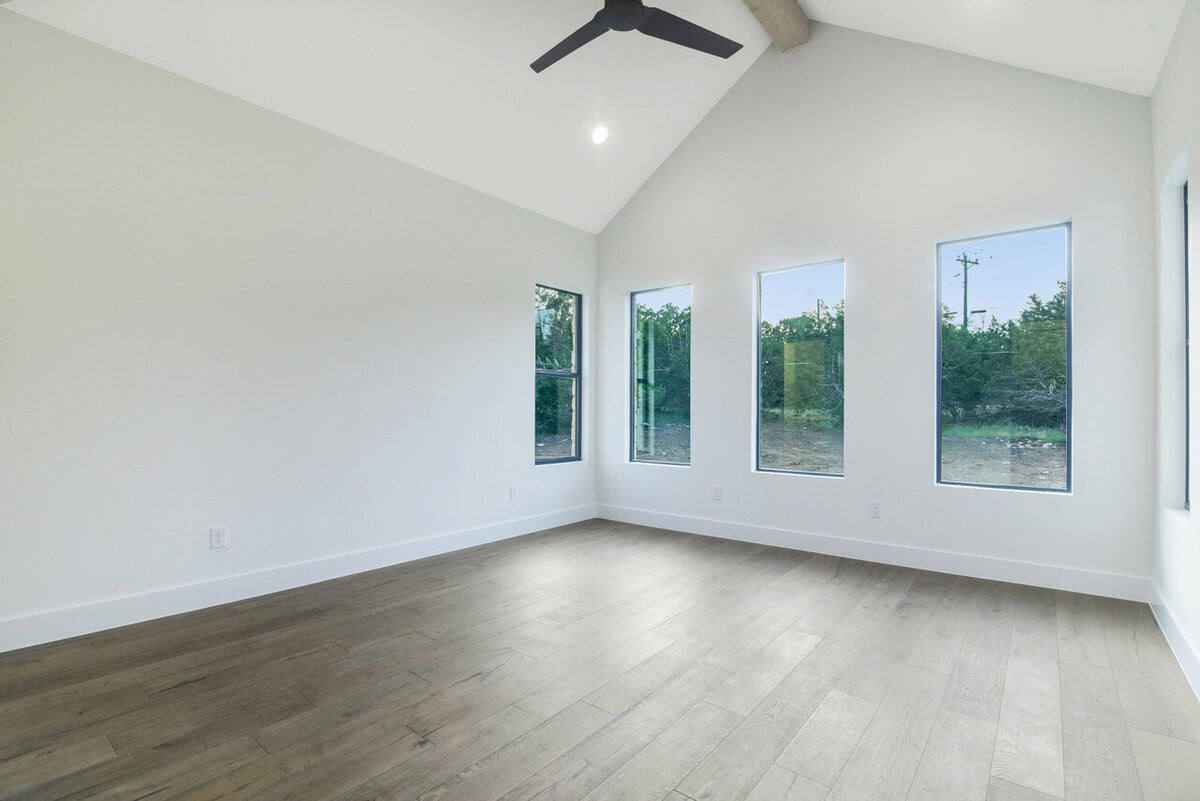 main bedroom with wood floors, white walls and black windows