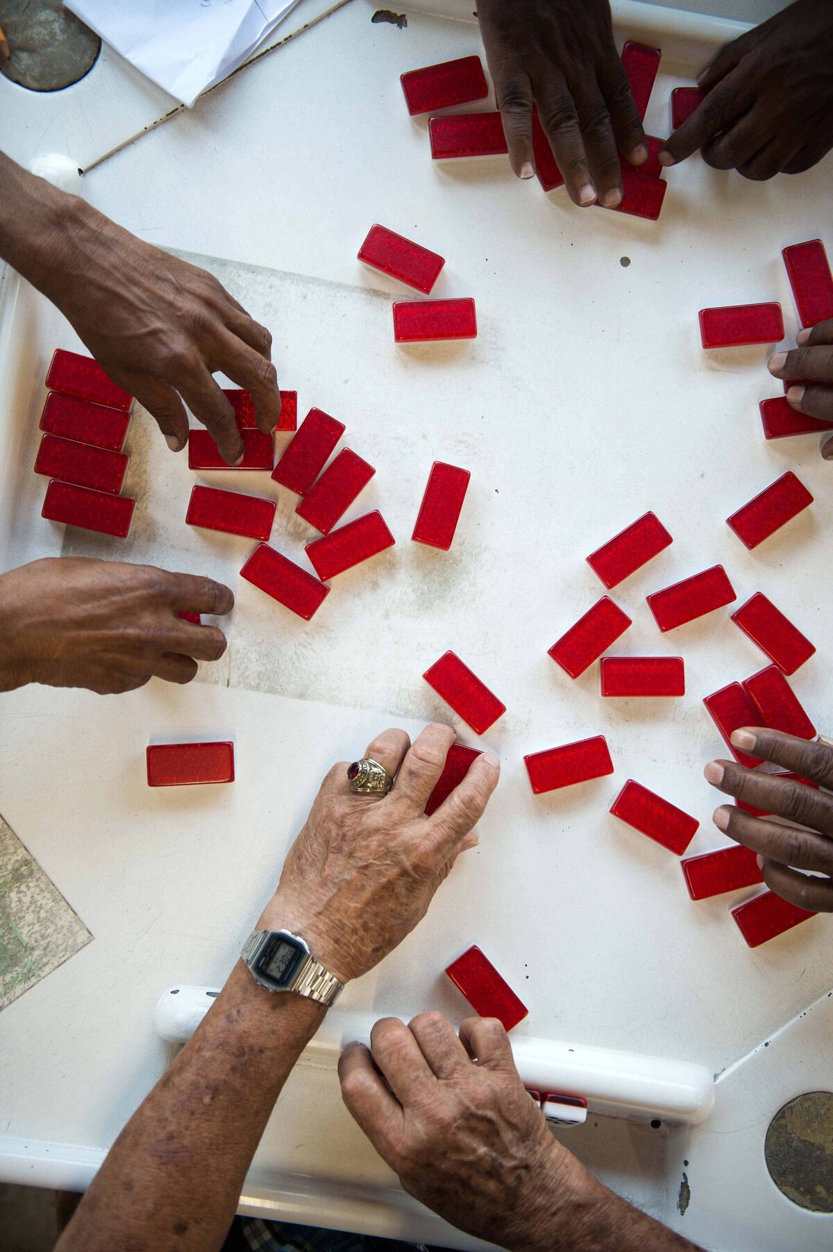 Hands reach for red dominos at Domino Park in Little Havana