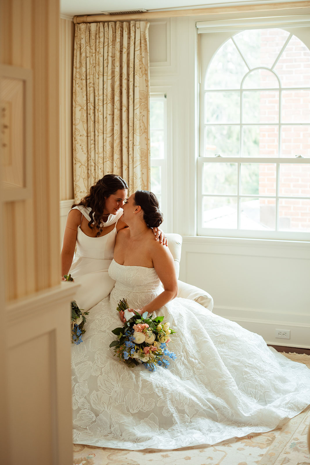 Two brides sitting down while looking into each other's eyes