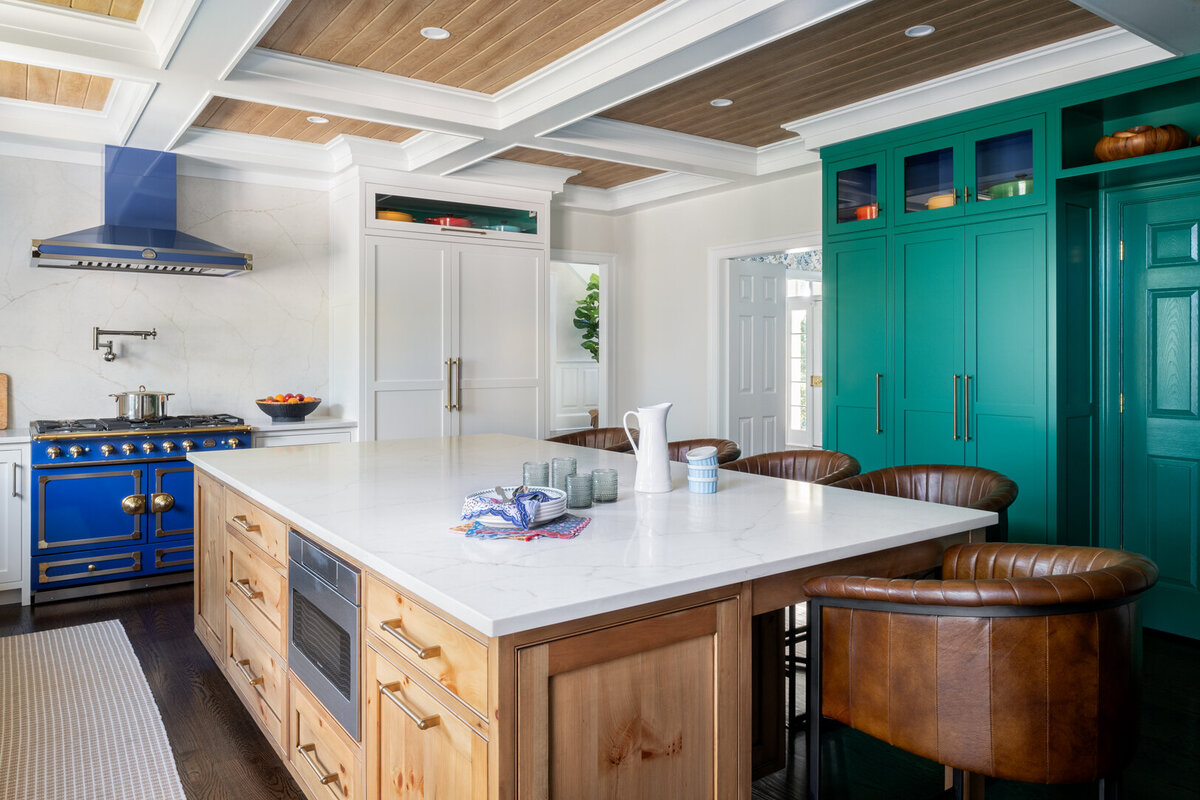 white kitchen with marble and wood island top and teal cabinet
