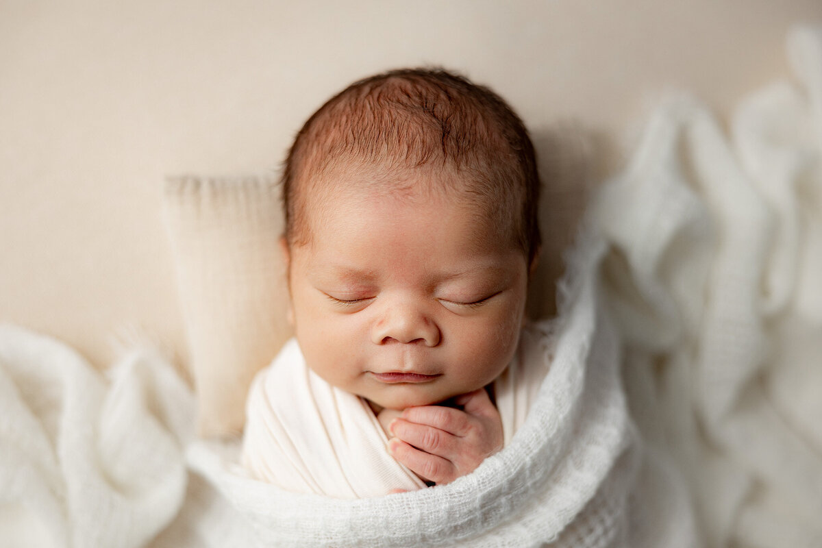 infant sleeping swaddled in soft fabric for photography session in gaylord michigan