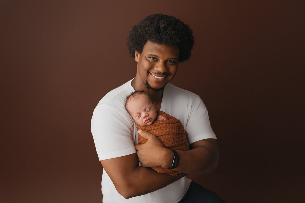 dad holding baby smiling during portraits of baby in phoenix