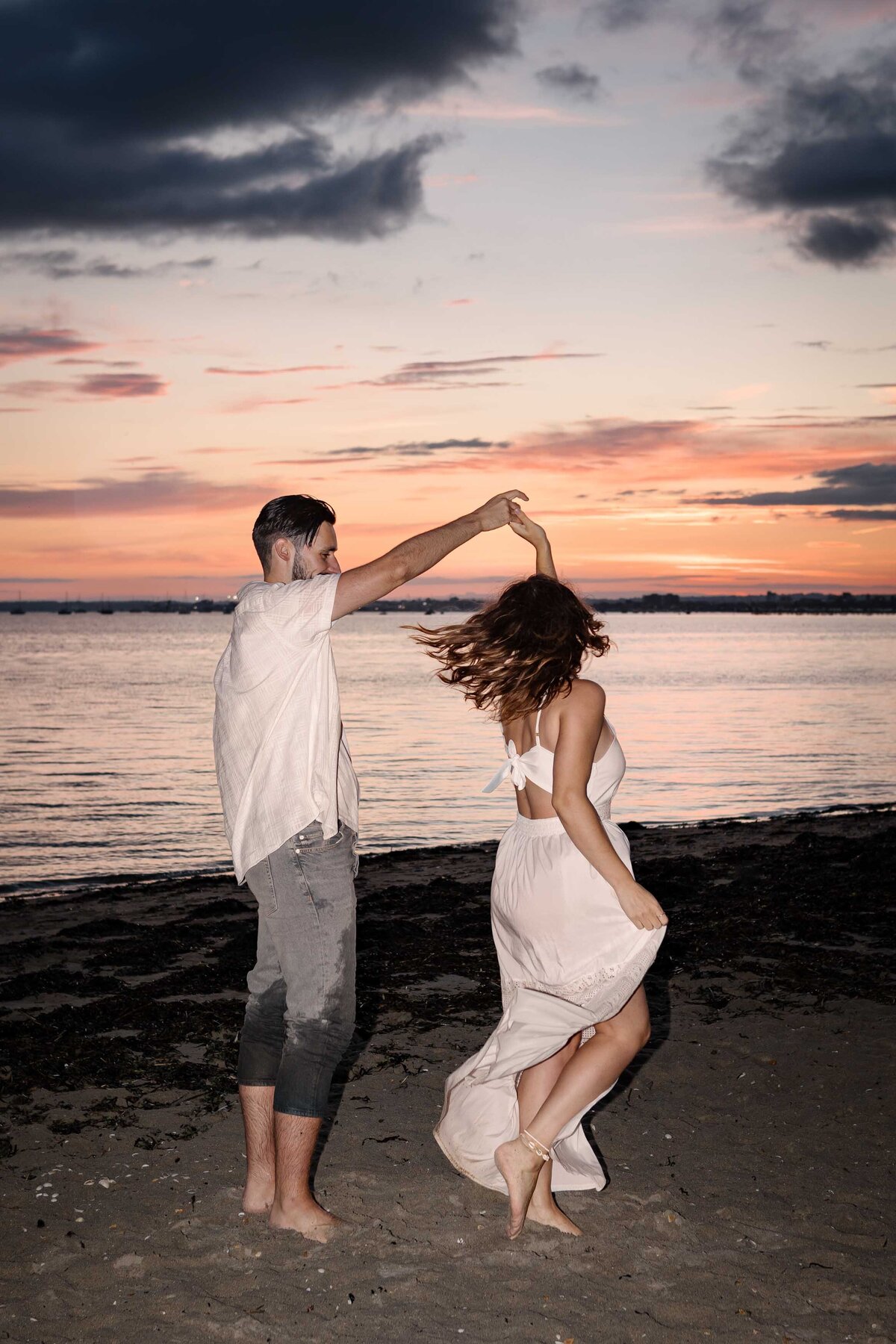 A couple dancing on the beach at sunset in Poole