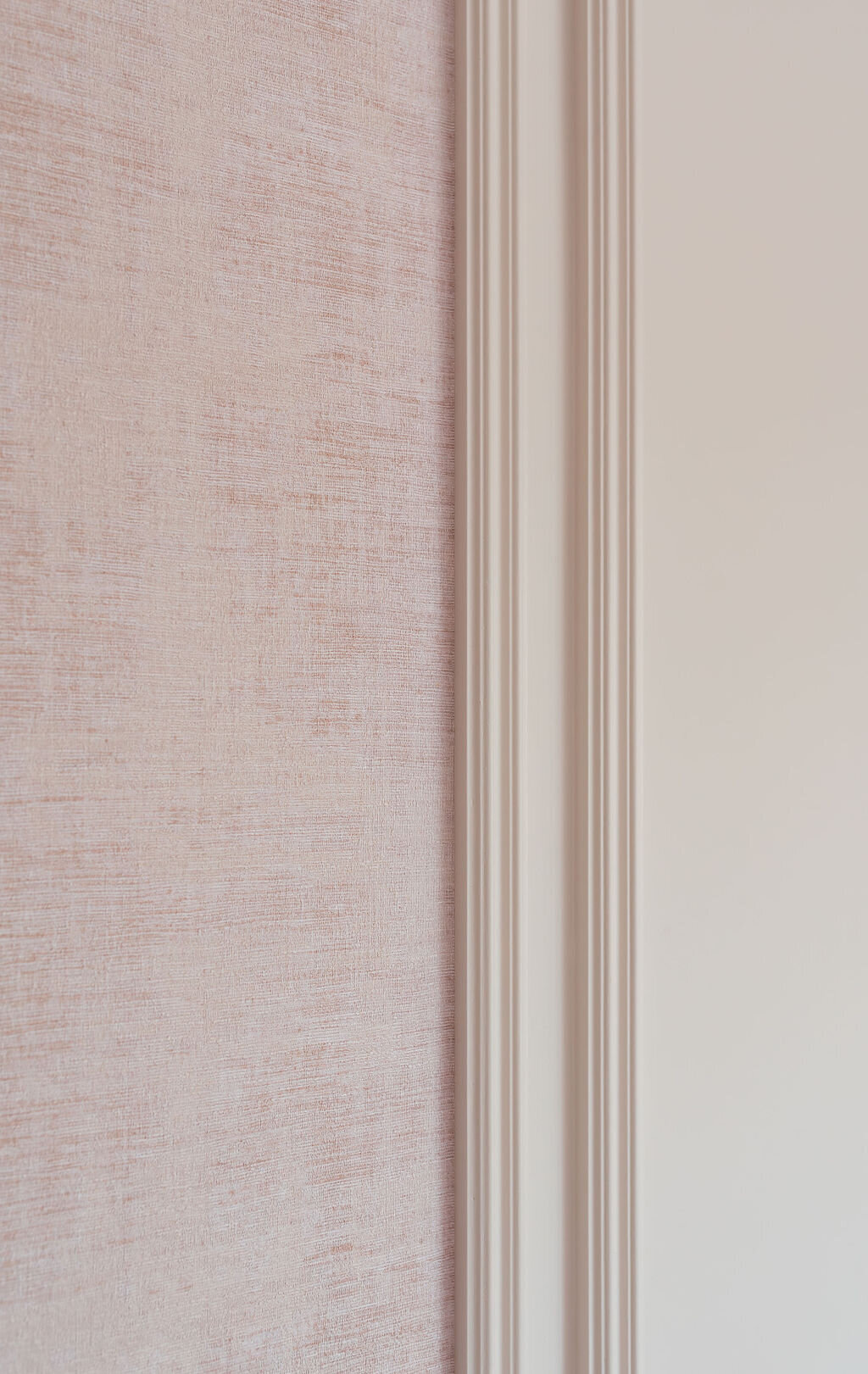 A close-up view of the soft pink wallpaper and pale pink paint on a girl's bedroom.