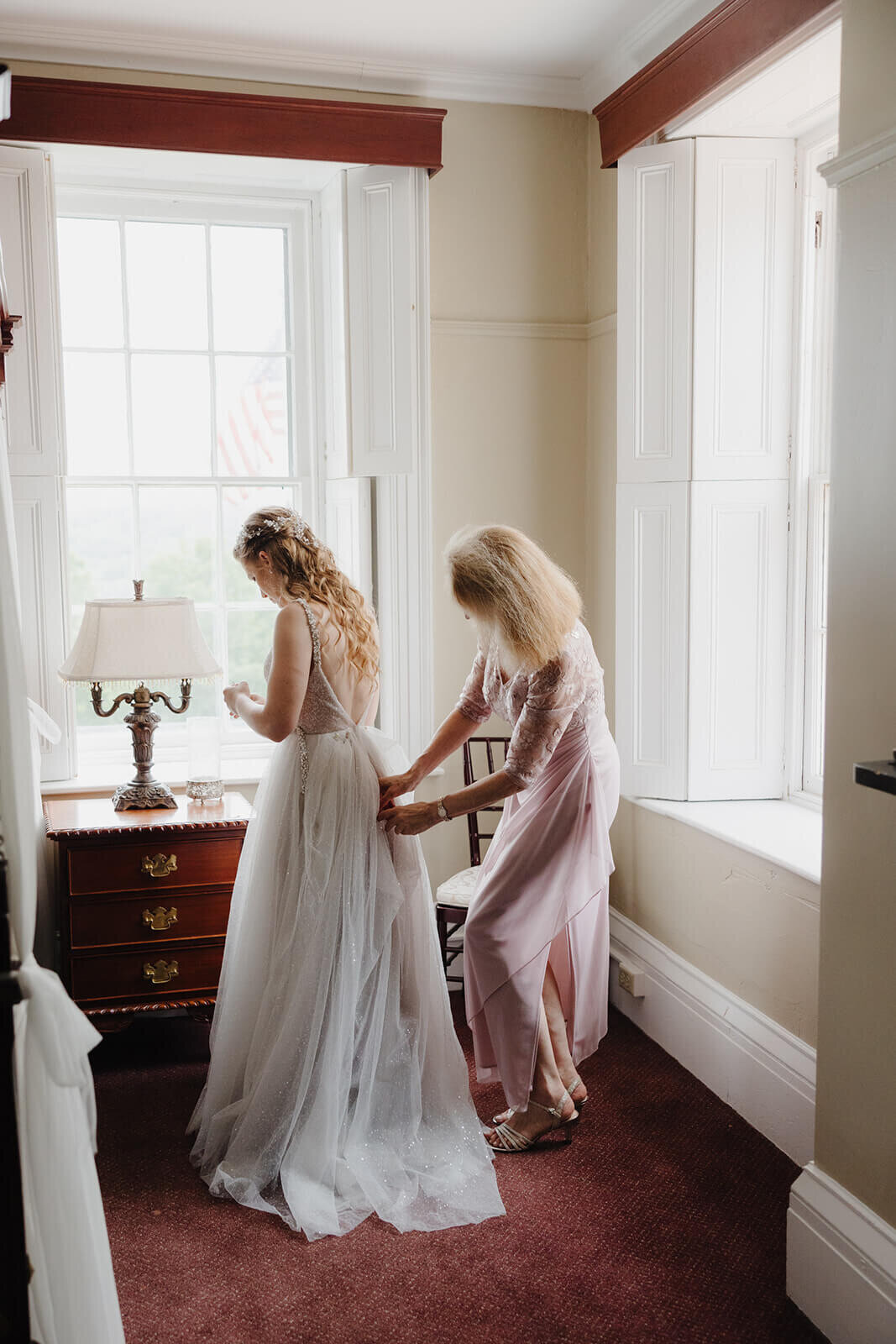 Bride having dress ffixed by bridesmaids before wedding at The Mansion at Keuka Lake, NY