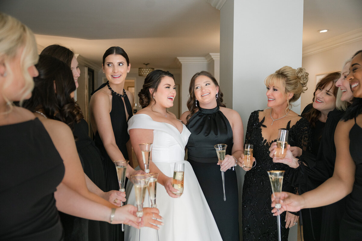 bride and bridesmaids cheering with champagne at The Adolphus in Dallas, capturing a fun and celebratory moment during the wedding day.