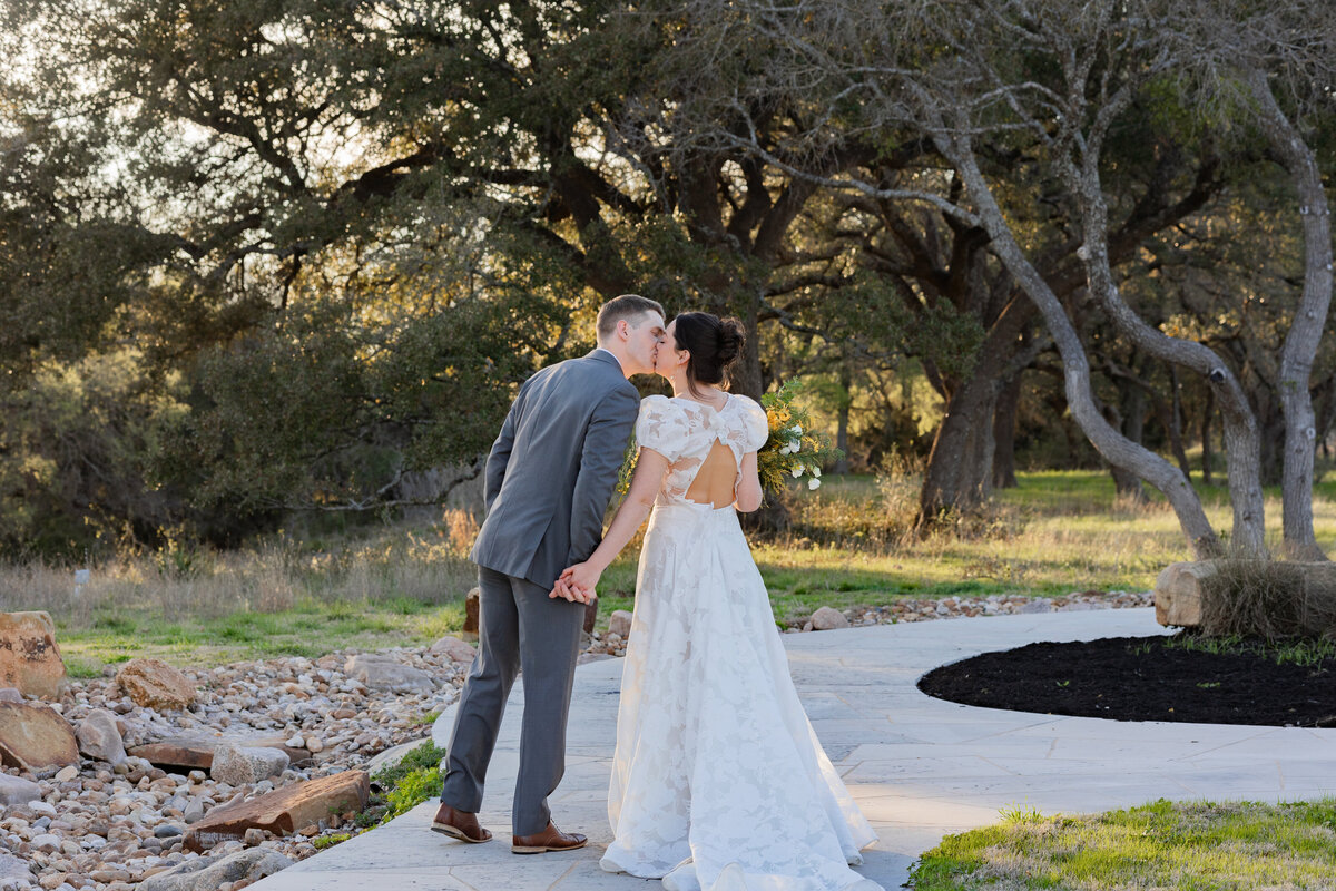 bride and groom kissing and walking a cement walk path at HighPointe Estate in Austin Texas by destination wedding photographer Amanda Richardson Photography