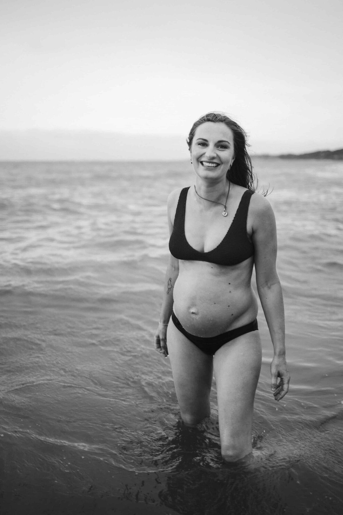 Black and white photo of pregnant woman in bikini at beach. By Delanie, Melbourne maternity photographer 