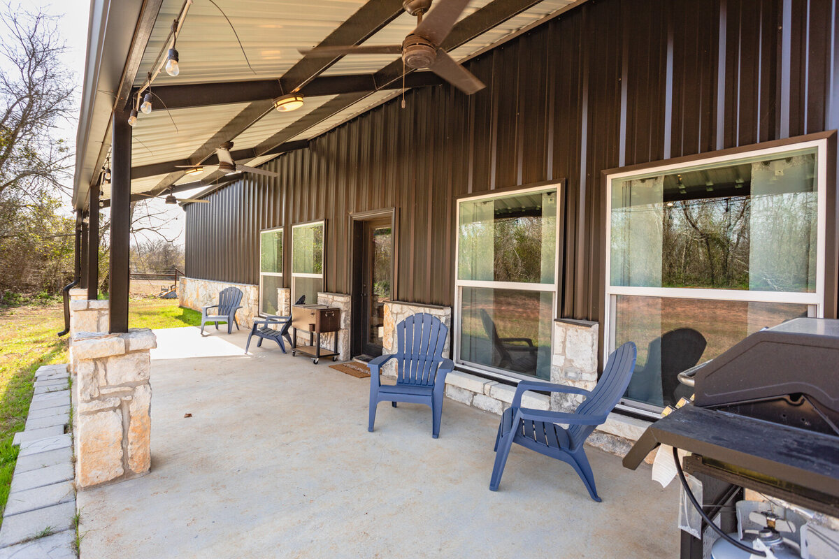 Covered patio with fans, grill and plenty of seating in this five-bedroom, 3-bathroom vacation rental house for up to 10 guests with free wifi, private parking, outdoor games and seating, and bbq grill on 2 acres of land near Waco, TX.