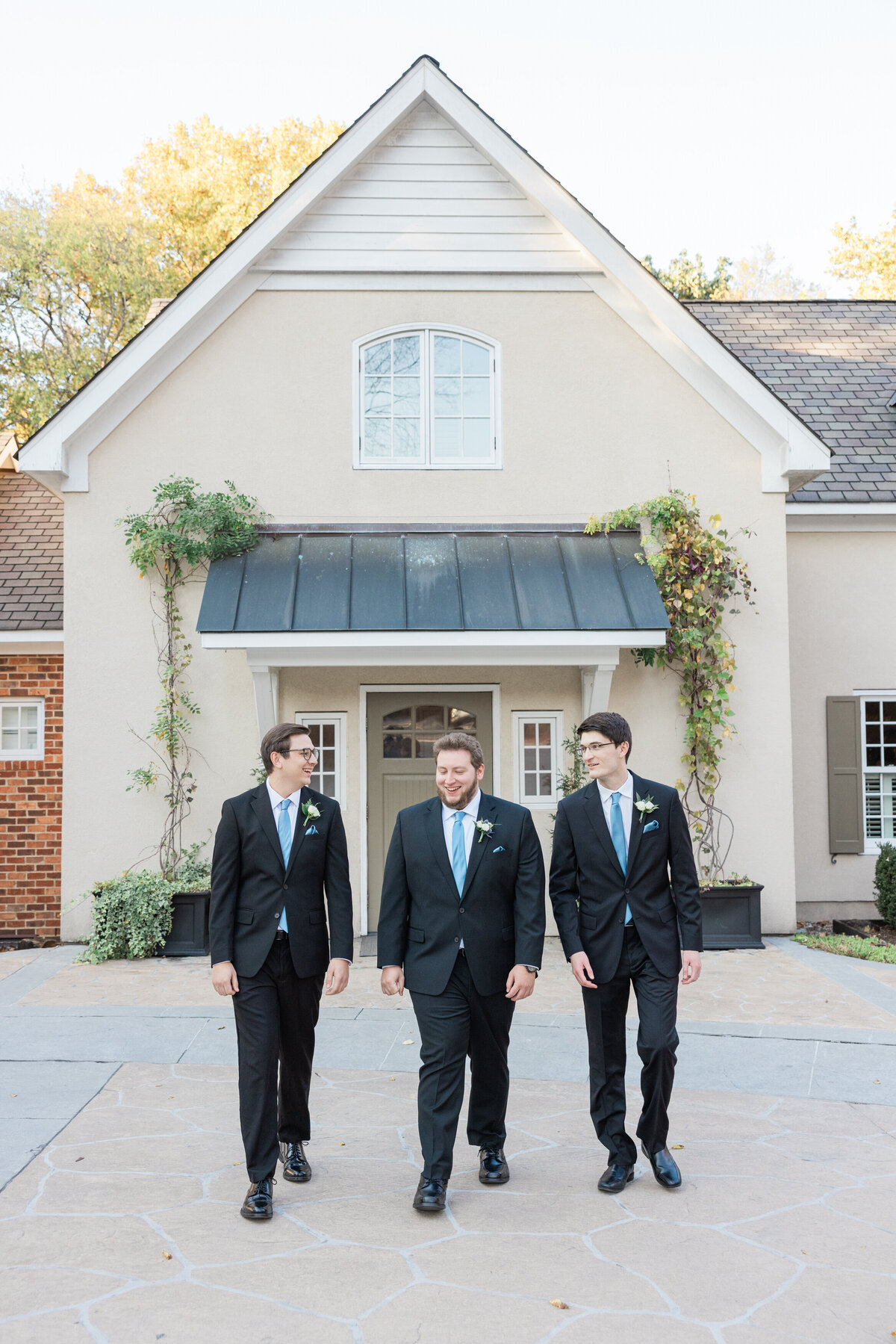 A newlywed with two groomsmen on either side of him