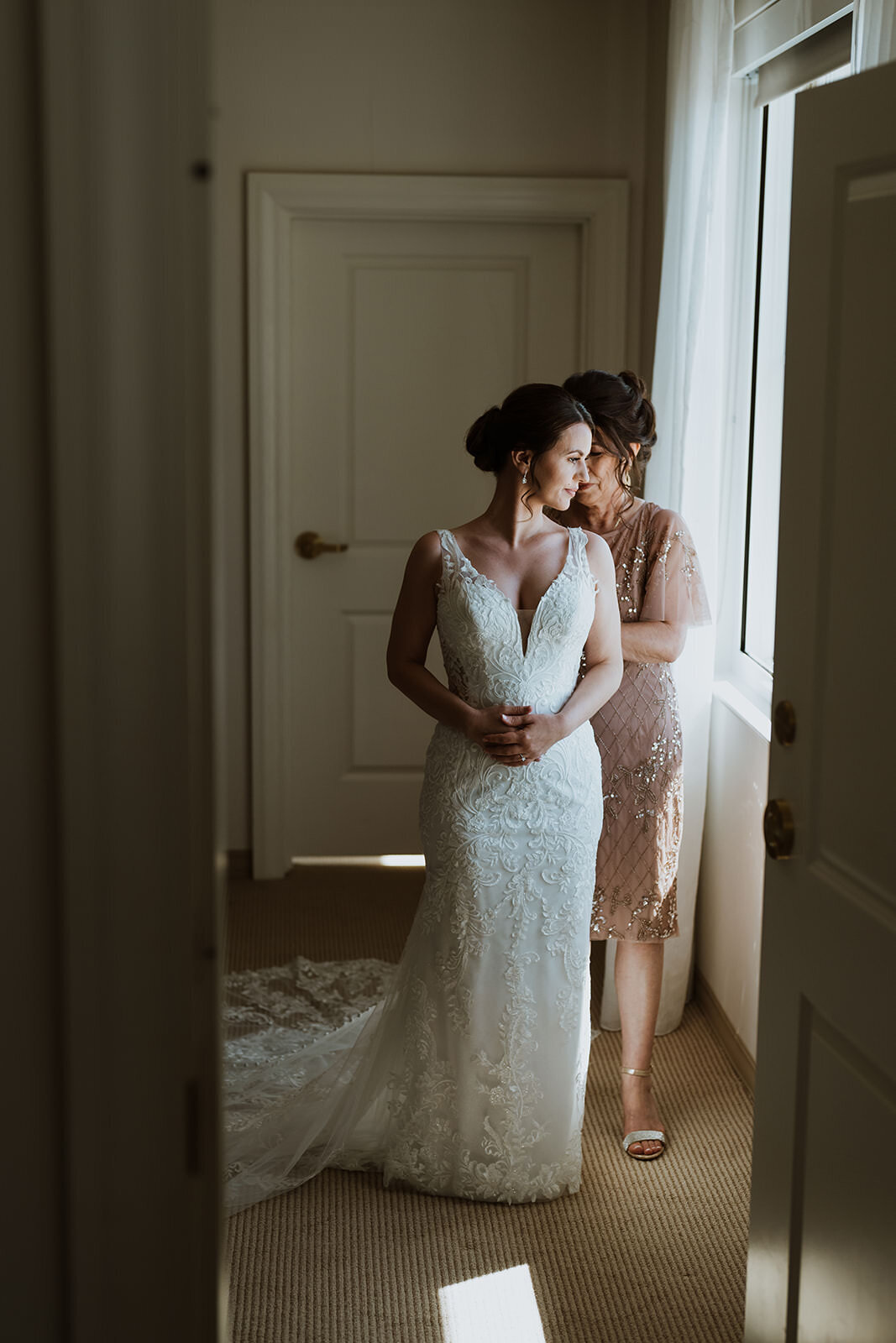 bride getting help from her mother to get into her wedding dress