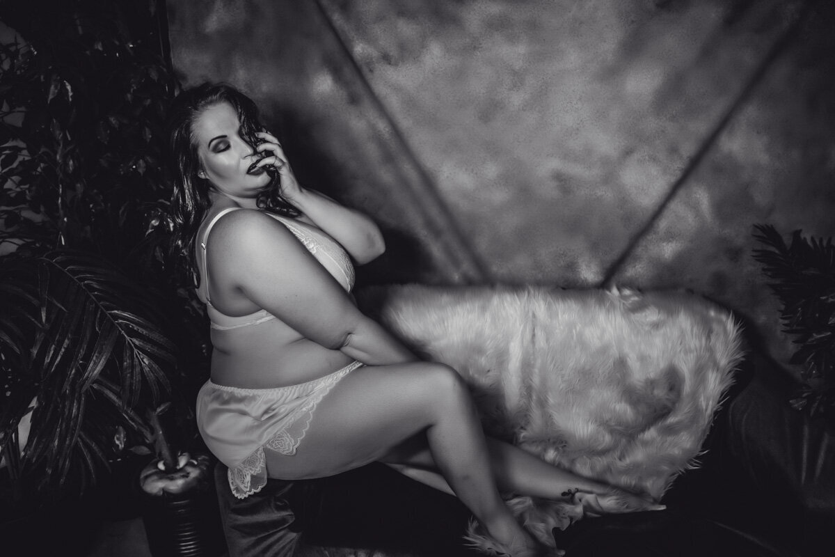 Black and white photo of woman sitting in a lignerie set on a couch in  Minneapolis Mn