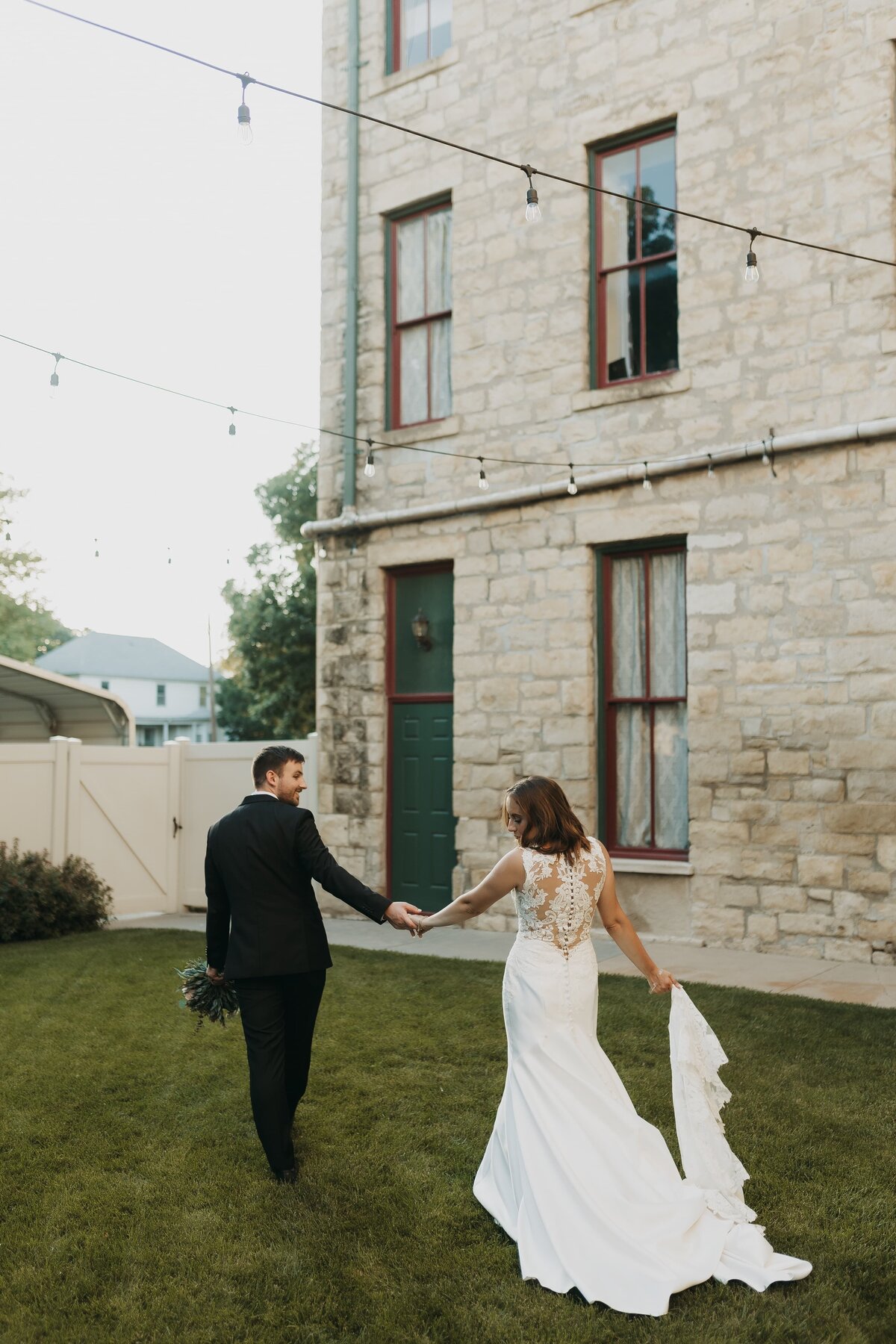 groom holding brides hand while she looks over her shoulder