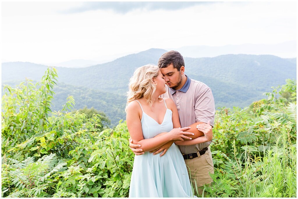 couple snuggling with the mountains in the background