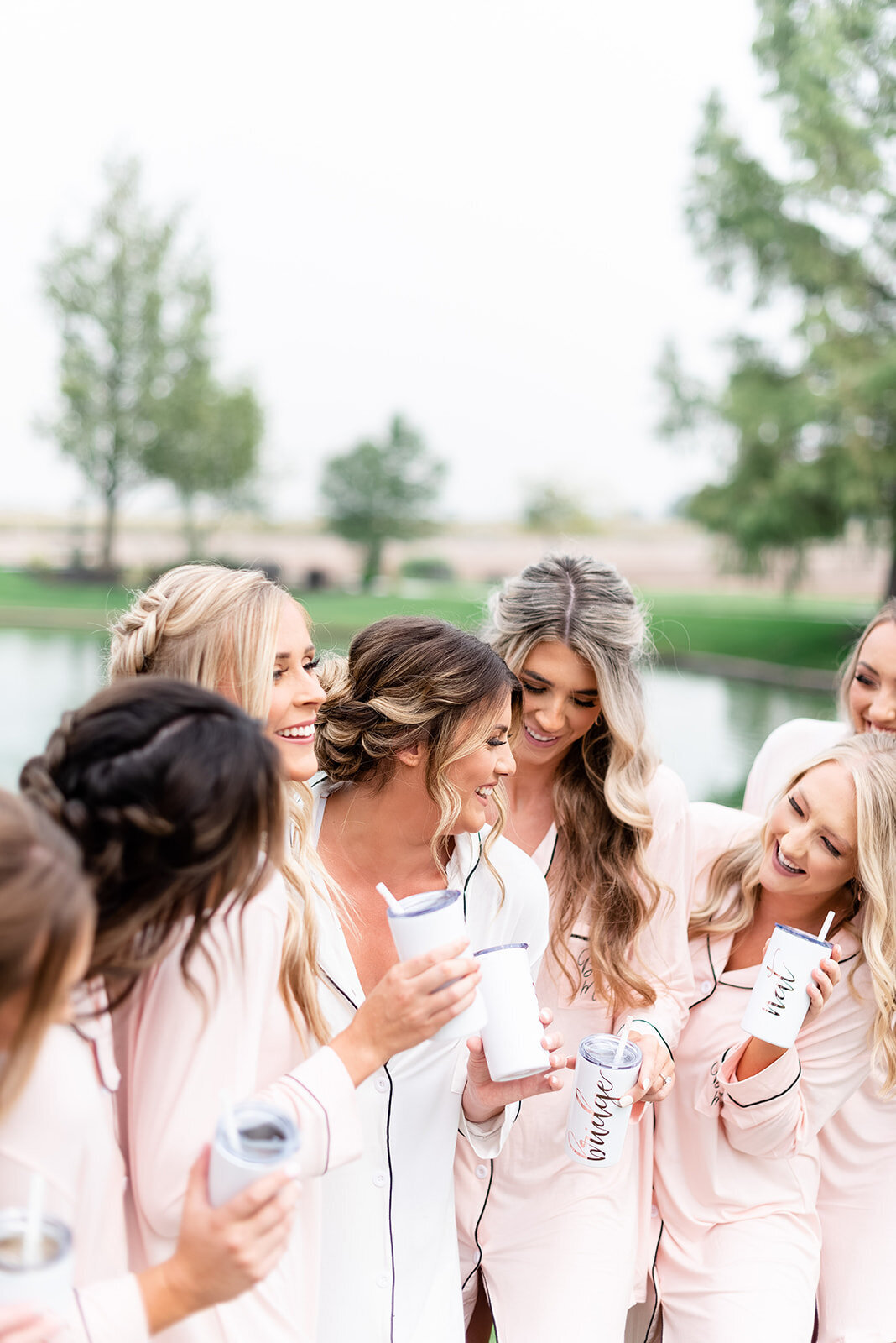 Bridesmaids in pink robes in front of pond at Light and airy wedding photography by the Best Boise Wedding Photographers