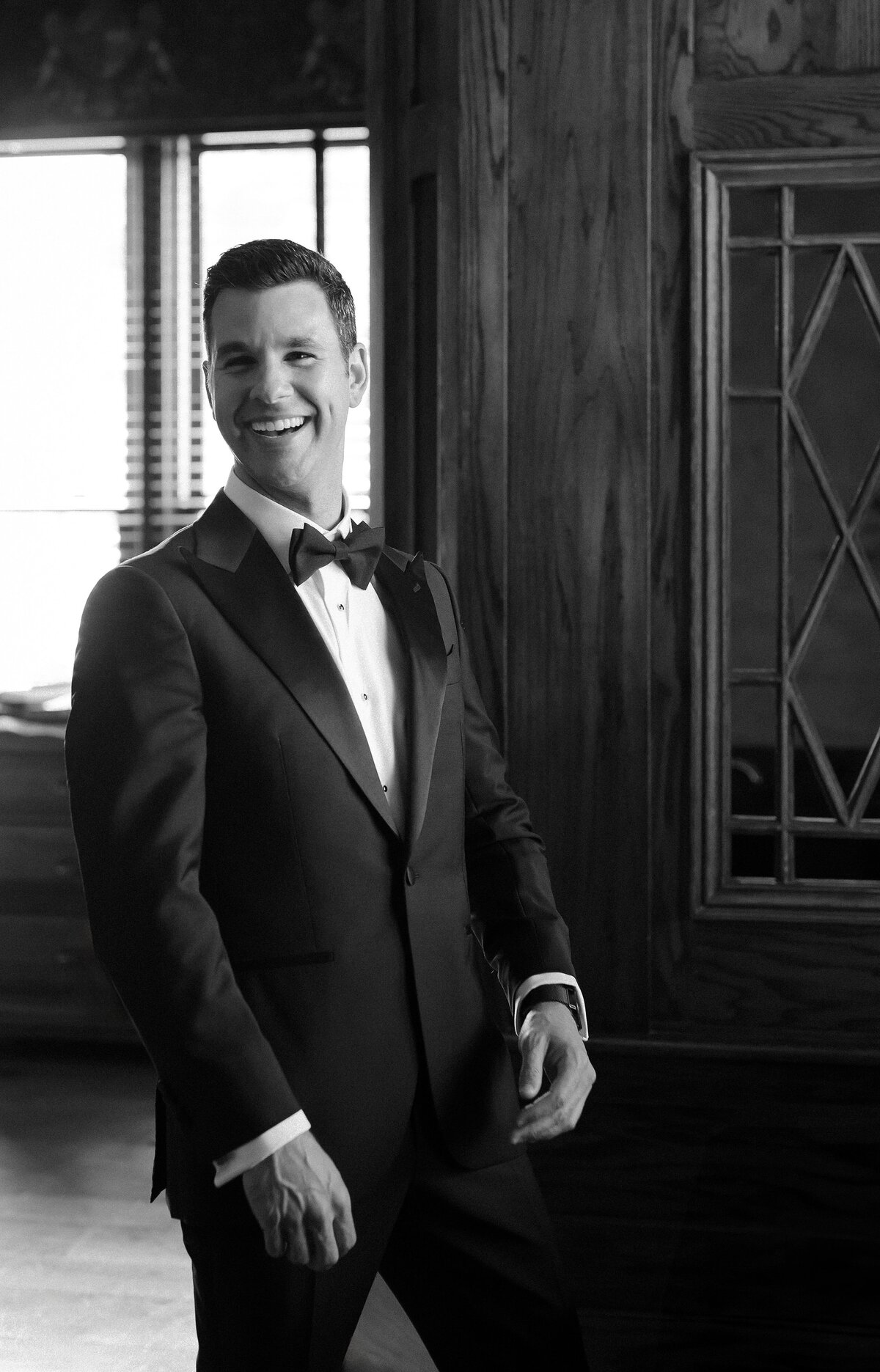 Groom laughs towards camera as he gets ready at The Chanler in Newport.