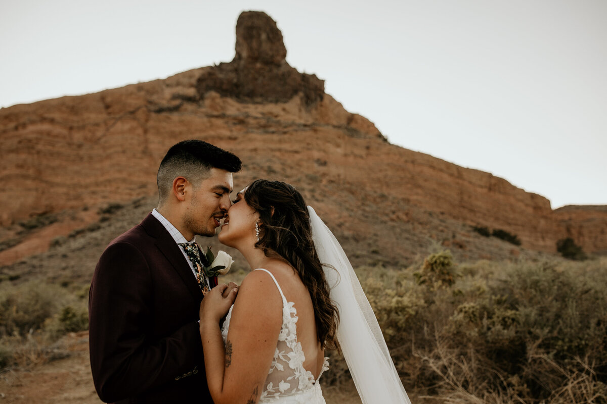 bride and groom with their noses together in the desert