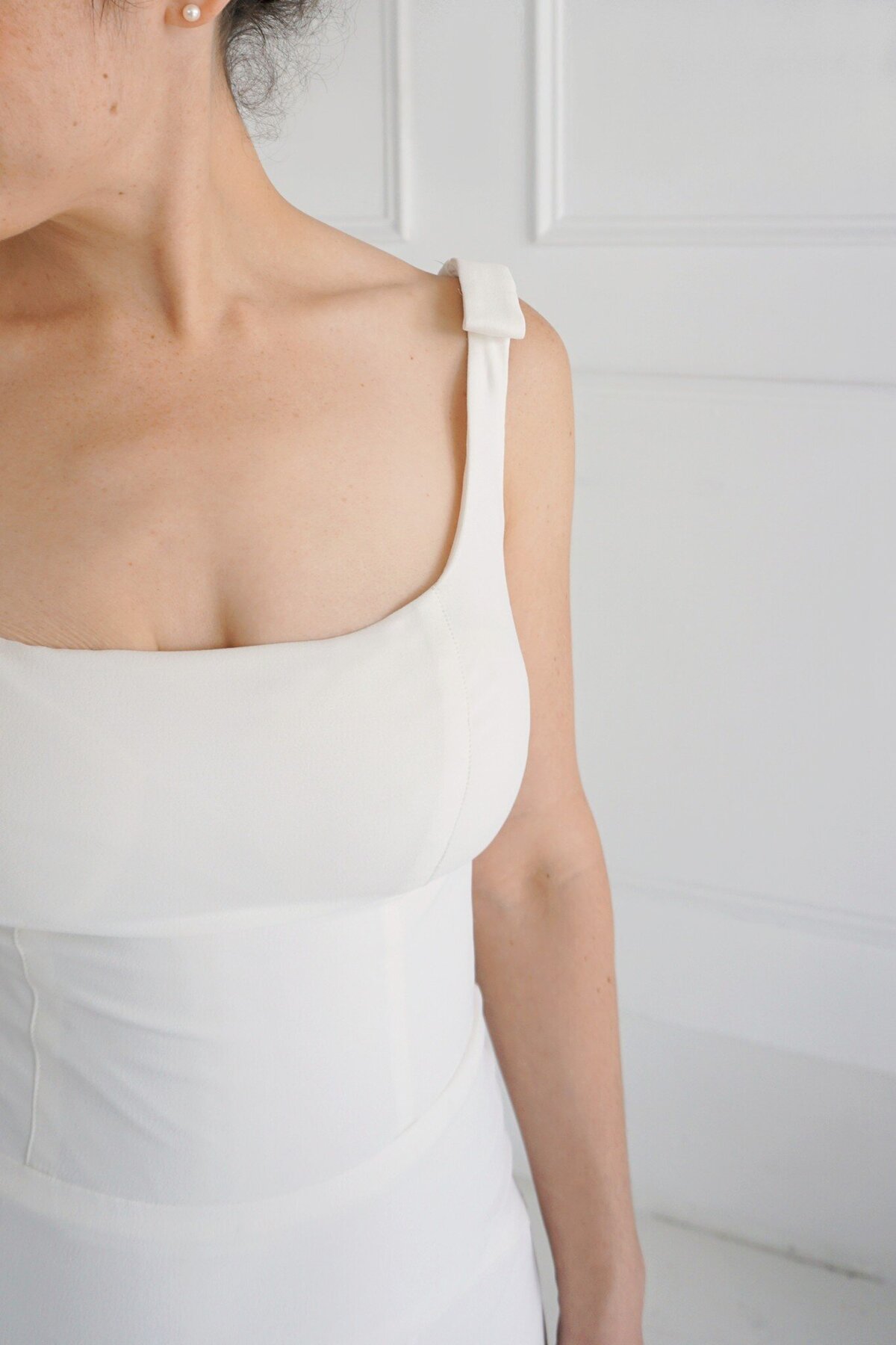 Detail shot of the crepe bodice on the Jealine bridal style with its shoulder bows and rounded square neckline.