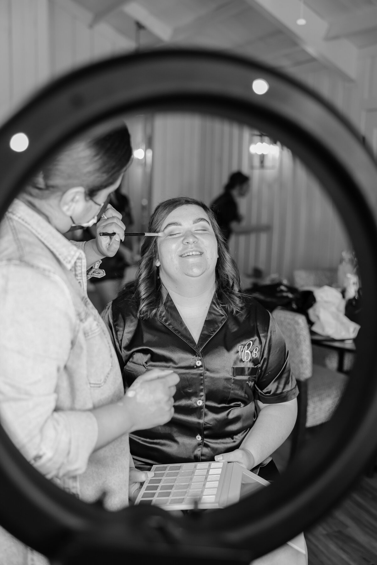 black and white image of bridesmaid in satin robe  eye makeup  at wedding Austin Texas